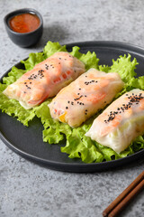 Vietnamese spring rolls of prawn and vegetables in rice paper on grey light background. Close up. Asian cuisine. Vertical format.