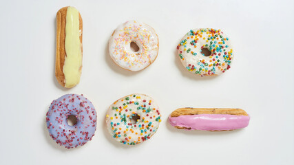 No more diets. Top view of various sweets, colorful tasty and fresh donuts and eclairs
