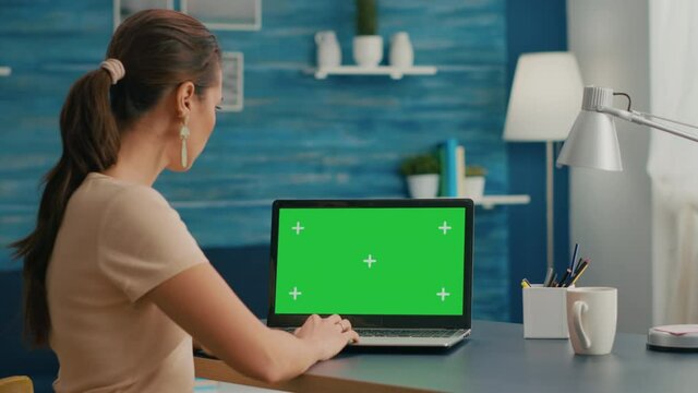 Freelancer woman searching business advertising using isolated pc standing in home office studio. Caucasian woman working with laptop computer with mock up green screen chroma key