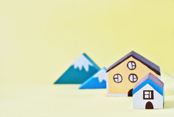 toy houses and mountains on yellow background. village suburban living. buying house in a country. slow liffestyle