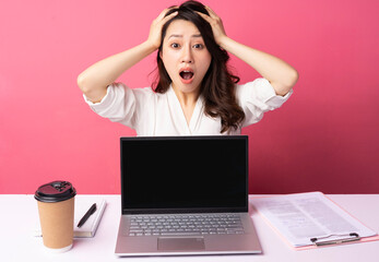 Young Asian businesswoman sitting working with expression on background