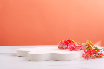 Closup of white stand and colorful decorative branches on the white table against bright orange wall.Empty space