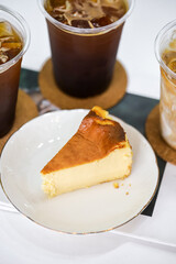 Basque cheesecake burnt bakery delicious cheesecake with 3 glassed of iced coffee in the background on the table.