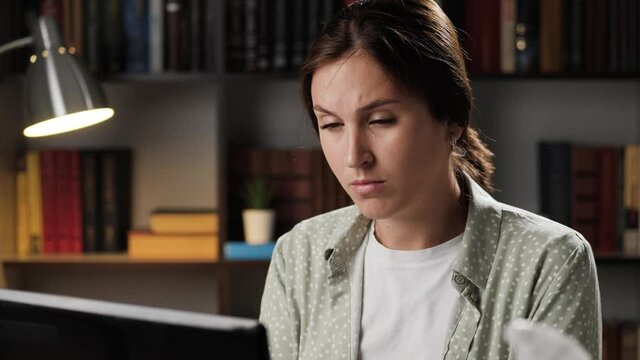 Fainting, exhaustion, shock, starvation concept. Tired woman in evening working at computer and experiences dizziness, she touches her head and loses consciousness and falls on table. Slow motion