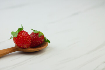 Stroberi or strawberries on wooden spoon with isolated white background. Bright photography concept, copy space for text.