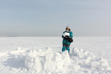 Happy woman  building an igloo on the snow
