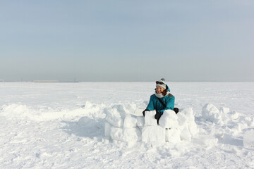 Happy woman  building an igloo on the snow