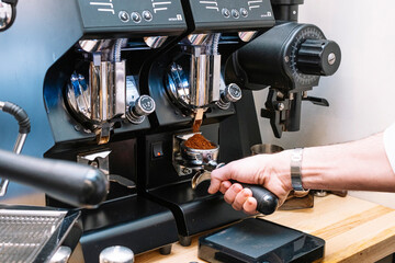 Waiter's hand supplying ground coffee in coffee shop