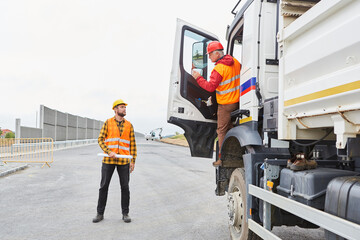 LKW Fahrer redet mit Bauarbeiter auf der Baustelle