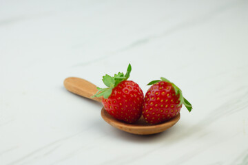 Stroberi or strawberries on wooden spoon with isolated white background. Bright photography concept, copy space for text.