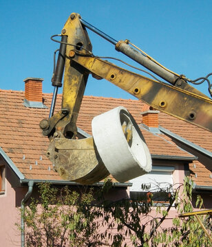 Loading bucket excavator lifts the concrete cylinder in a populated area