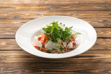 Vegetable salad with tomatoes, arugula, chicken, parmesan cheese and rye croutons