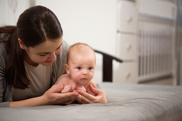 Young mother holding her baby in the bedroom.