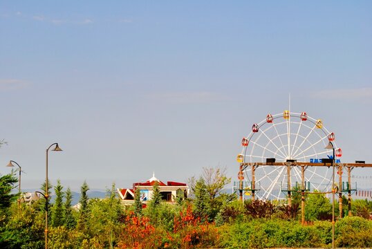The observation ferris wheel tourist attraction facing Caucasus mountains against blue sky. Gabala, Gebele, Azerbaijan.