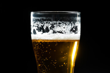 Close-up of a beer glass with fallen foam on a black background