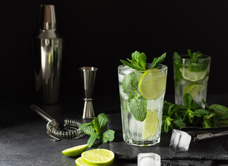 Refreshing summer mojito cocktail with ice cubes, fresh mint and lime on black.