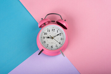 A table clock with a Pink blue and purple background flat lay shot