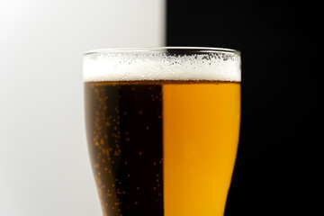 Close-up of a glass of light and dark beer on a white-black background. Creative shot of a glass of beer