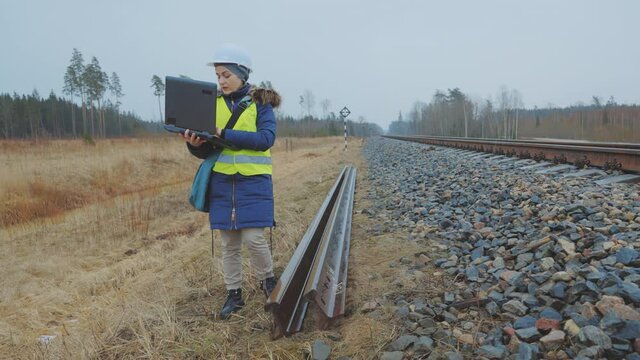 Railroad Worker With Laptop Near Unused Rails
