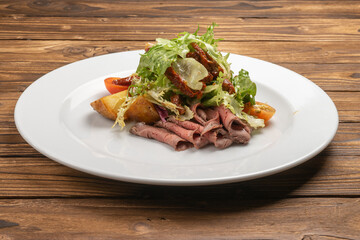 Warm salad with roast beef, baked potatoes and sun-dried tomatoes
