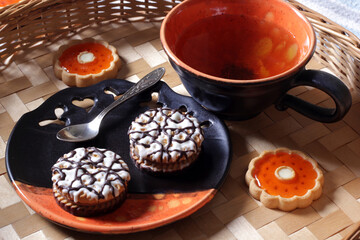Sweet breakfast. Tea with cookies with chocolate vanilla glaze and orange marmalade