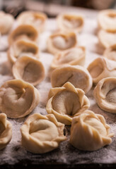many dumplings with handmade meat on a wooden board sprinkled with flour