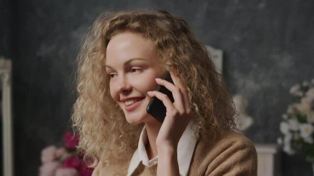Close up of a young caucasian woman shy talking on a phone indoors