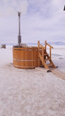 wooden outdoor sauna during a cold winter day with steam going out of the open door