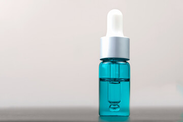Cosmetic turquoise bottle with pipette on white background with copy space, macro. Concept of cosmetology, medicine