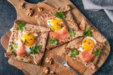 Crepes with eggs, salmon, spinach and nuts. Traditional dish galette sarrasin or buckwheat crepe,...