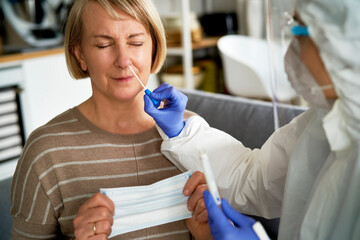 Female doctor taking a nasal swab test from a senior woman
