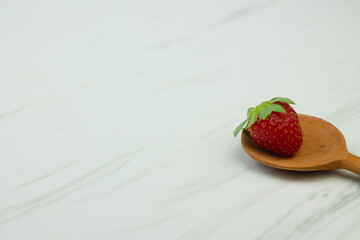 Stroberi or strawberries on wooden spoon with isolated white background. Bright photography concept, copy space for text.