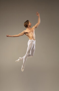 Aesthetic. Young and graceful ballet dancer isolated on studio background in flight, jump. Art, motion, action, flexibility, inspiration concept. Flexible caucasian ballet dancer, moves in glow.