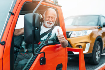Handsome senior man working in towing service on the road. Roadside assistance concept.