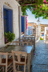 Cycladitic alley with a narrow street and  an exterior  of a traditional  tavern with chairs and tables  in Chora kythnos,cyclades, Greece.