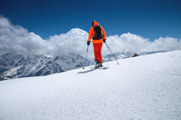 Portrait of a young male athlete skier in a ski tour on skis on the background of snow-capped...