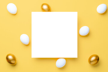 Easter background yellow. Golden, white colour egg on pastel yellow background in Happy Easter decoration. Flat lay, top view.