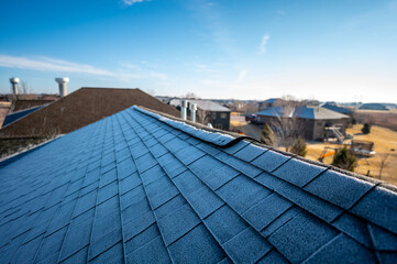 Contrast of frost line on a shingle roof as the sun rises and melts it