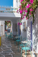 Cycladitic alley with a narrow street and  an exterior  of a traditional  whitewashed cafe with chairs and tables  in Chora kythnos,cyclades, Greece.