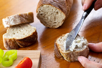 Woman spread basil and parsley cream over baguette. Selective focus.