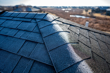 Contrast of frost line on a shingle roof as the sun rises and melts it