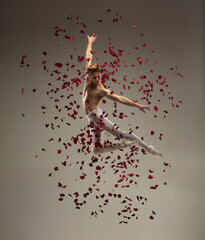 Romance. Young and graceful ballet dancer on studio background in flight, jump with rose petals. Art, motion, action, flexibility, inspiration concept. Flexible caucasian ballet dancer, moves in glow.