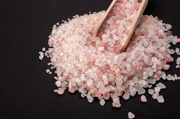 Pink himalayan salt. Himalayan Pink Rock Salt In wooden Spoon on black background. Fine grains of...