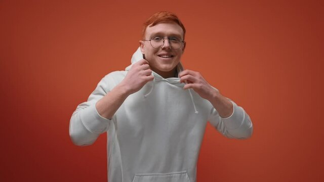 Smiling male with red hair admiring himself, adjusting hairstyle and glasses