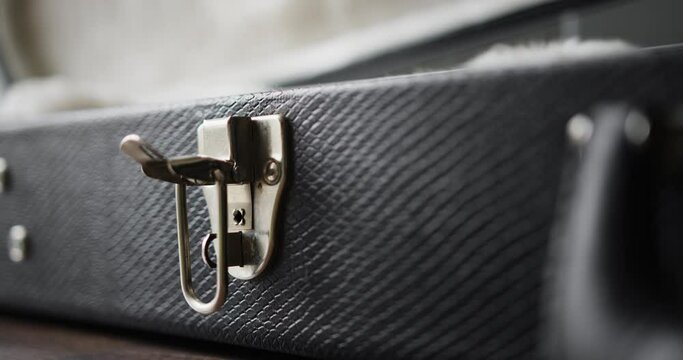 Closeup shot of person open black guitar case lock.