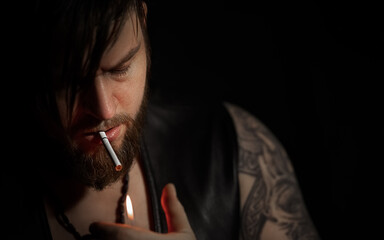 Obraz premium Brutal bearded man with a cigarette in a recording Studio with guitar on the black background