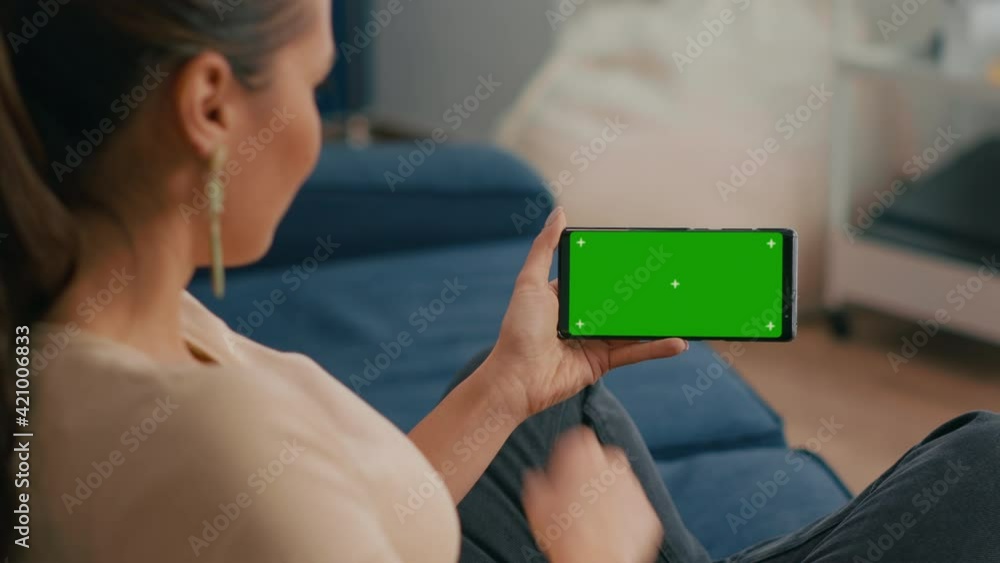 Aufkleber close up of woman holding smartphone with mock up green screen chroma key display while sitting on s