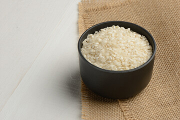 Arroz redondo en un bol de cocina negro en la mesa blanca