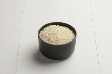 Arroz redondo en un bol de cocina negro en la mesa blanca