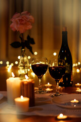 Romantic composition with burning candles and wine on table home at night